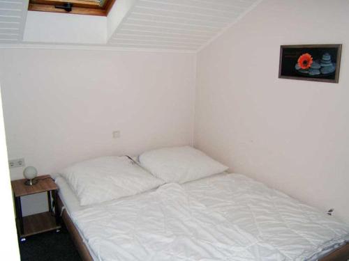 ein kleines Schlafzimmer mit einem Bett mit weißer Bettwäsche in der Unterkunft "Friesenhörn" 31 Merchant in Horumersiel