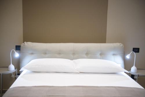 a bedroom with a white bed with two lamps at Rooms Don Alfonso in Parma