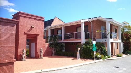 a red brick house with a balcony on a street at Sanno Marracoonda Perth Airport Hotel in Perth