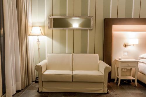 a living room with a white chair and a bed at Le Ali Del Frassino in Peschiera del Garda