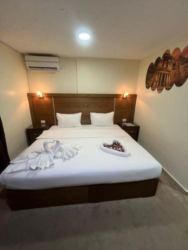 a bedroom with a large bed with white sheets at Petra Aretas Hotel in Wadi Musa