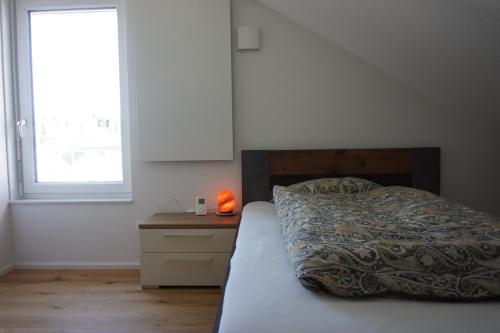a bedroom with a bed and a nightstand and a window at Natur & Ruhe, neu & zentral, im Herzen von Freudenstadt in Freudenstadt