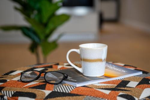 a cup of coffee and a book and glasses on a table at Hotel Royal in Noordwijk
