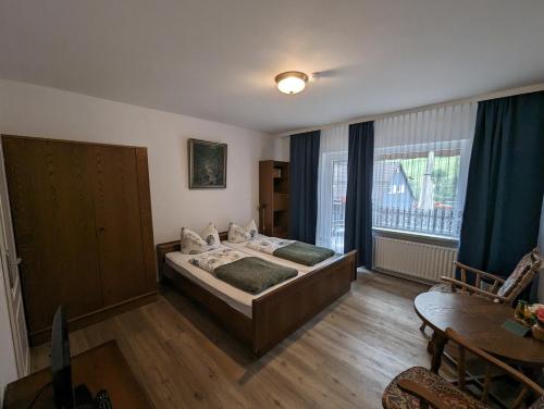 a bedroom with two beds and a table and a window at Haus Am Waldesrand in Herzberg am Harz