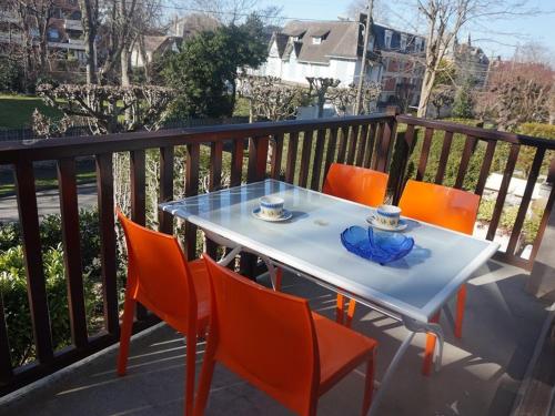 - une table avec des chaises orange et une plaque bleue dans l'établissement Appartement T2 au cœur de Cabourg avec balcon, parking & acceptant animaux - FR-1-465-16, à Cabourg