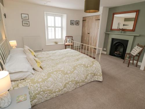 a bedroom with a bed and a fireplace at Lavender Cottage in Alnwick