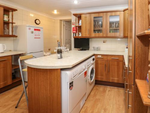 a kitchen with wooden cabinets and a white dishwasher at The Old Assembly Rooms in Bishop Auckland