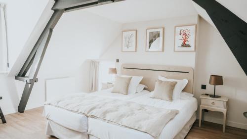 biała sypialnia z dużym białym łóżkiem z białymi poduszkami w obiekcie Hôtel De La Marine w mieście Arromanches-les-Bains