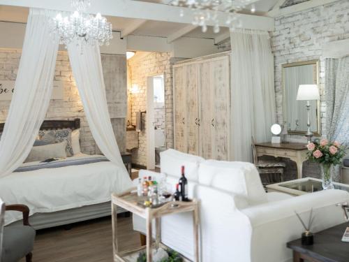 a bedroom with a white bed and a chandelier at Rose and Ivy Cottages in Louis Trichardt