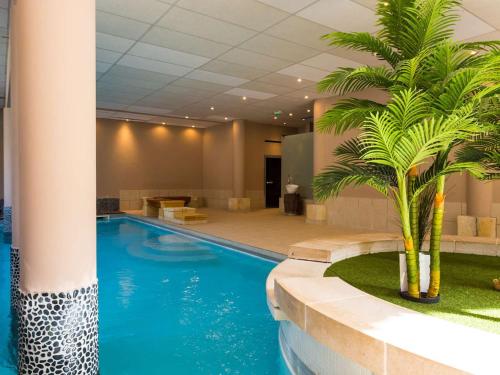 une piscine avec un palmier dans le hall de l'hôtel dans l'établissement Appartement Duplex 8 Pers Centre-Ville Saint-Lary Soulan avec Piscine, Hammam et Sauna - FR-1-296-425, à Saint-Lary-Soulan