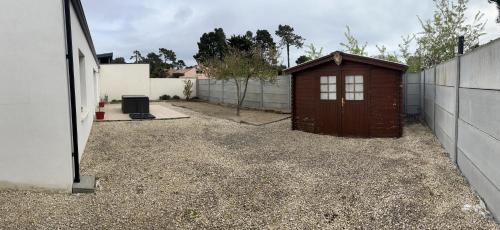 a small shed in a yard next to a fence at Charmante maison entre mer et forêt in Saint-Hilaire-de-Riez