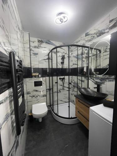 a bathroom with a shower with a toilet and a sink at Apartament Łąkowa z tarasem in Brodnica