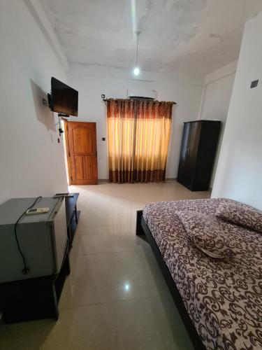 a bedroom with a bed and a television and a window at Hotel Mihira Village in Ambanpola