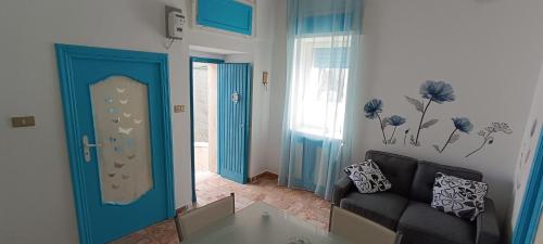 een woonkamer met een bank en een blauwe deur bij La Dimora di Netta in Carovigno