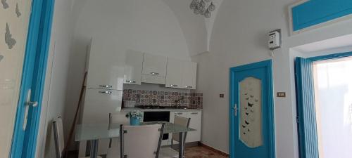 een keuken met een tafel en een blauwe deur bij La Dimora di Netta in Carovigno