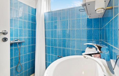a blue tiled bathroom with a shower and a sink at 3 Bedroom Gorgeous Home In Frvang in Fårvang