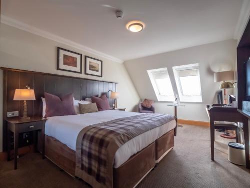 a hotel room with a large bed and a desk at The Loans Inn in Troon
