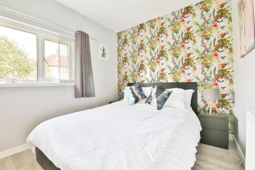 a bedroom with a white bed with a floral wallpaper at Garden Station Dwelling in Rumney in Cardiff