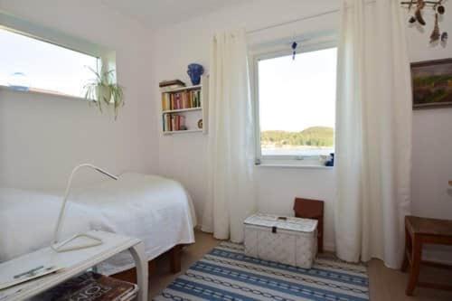 Habitación blanca con cama y ventana en Underbart hus med fantastisk havsutsikt & nära till bad, en Svanesund