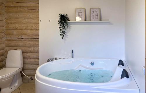 Gorgeous Home In Vggerlse With Kitchen في Bøtø By: حمام أبيض مع حوض استحمام بالماء الأزرق