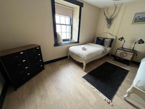 a bedroom with a bed and a dresser and a window at Charming and Cosy - Black's Land in Inveraray