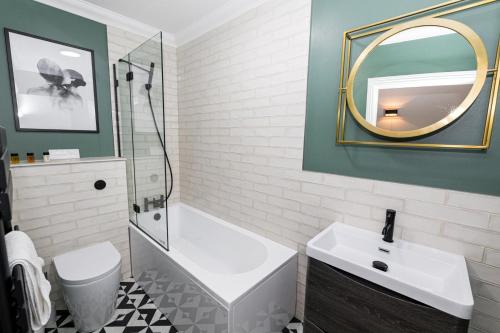 a bathroom with a tub and a sink and a mirror at Stylish home with garden near the beach in Bournemouth