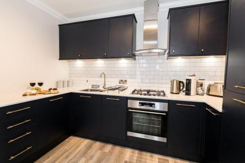 a kitchen with black cabinets and a stove top oven at Stylish home with garden near the beach in Bournemouth