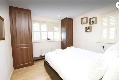 a bedroom with a white bed and a wooden door at A Delightful Retreat in Oxford in Oxford