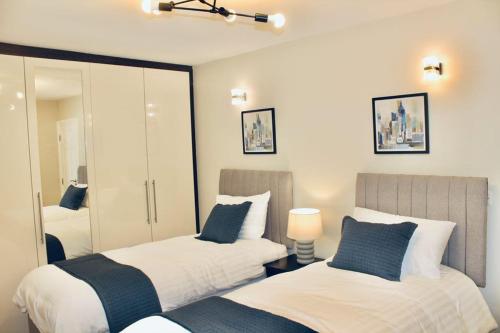 a bedroom with two beds and a mirror at A peaceful home with a garden in Reading