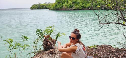 a woman sitting next to a body of water at Camping club apwisindo chandra in Kema