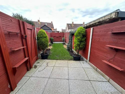 un jardín con una valla roja y una acera en Snug retreat in Reading en Earley