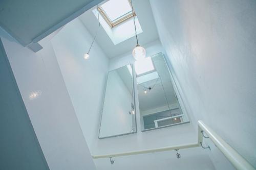 eine weiße Treppe mit einem Spiegel und einem Fenster in der Unterkunft Luxury retreat in Shirley North in Elmers End