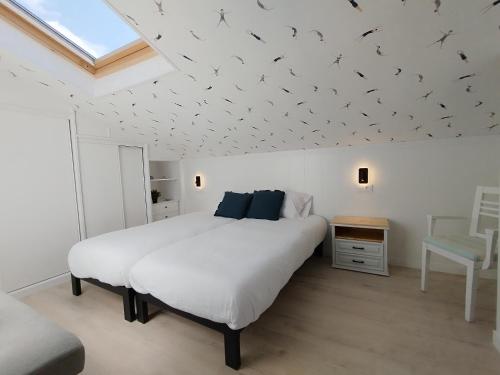 a bedroom with a large white bed with birds on the ceiling at Morriña Atlantica Duplex Playa America in Nigrán