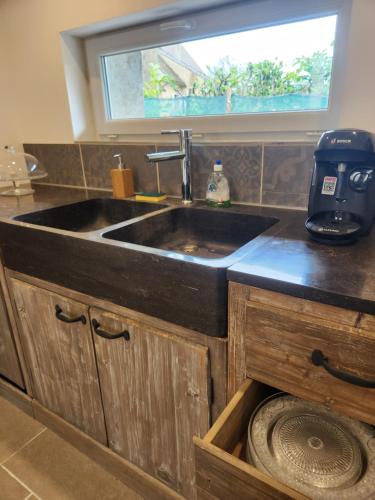 eine Küche mit Spüle und Fenster in der Unterkunft Le Nid'Ainay Maison de Village entièrement rénovée in Ainay-le-Vieil