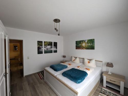 a white bedroom with a bed with blue pillows at Haus Am Waldesrand in Herzberg am Harz