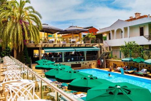 a pool with green umbrellas and a resort at Ambassador Hotel & Spa- All Inclusive in Kemer