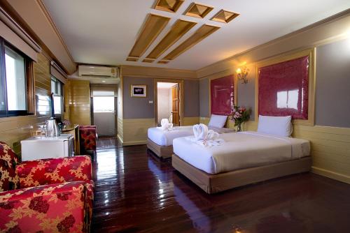 Ban Bang PhangにあるPEARL RESORT AND HOTEL เพิร์ลรีสอร์ทแอนด์โฮเทลのベッド2台とソファが備わるホテルルームです。