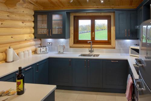 kuchnia z niebieskimi szafkami, umywalką i oknem w obiekcie Pheasant's Roost w mieście Foxton
