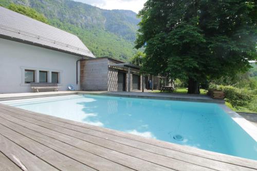 einem Pool mit Holzterrasse und einem Haus in der Unterkunft Family villa with swimming pool in Aiguebelette-Le-Lac in Aiguebelette-le-Lac