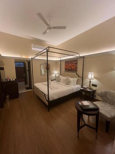 a bedroom with a four poster bed and a couch at Royal Orchid Metropole Mysore in Mysore