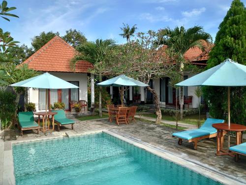 a resort with a swimming pool with chairs and umbrellas at Tunjung Kuning Cottage in Nusa Penida