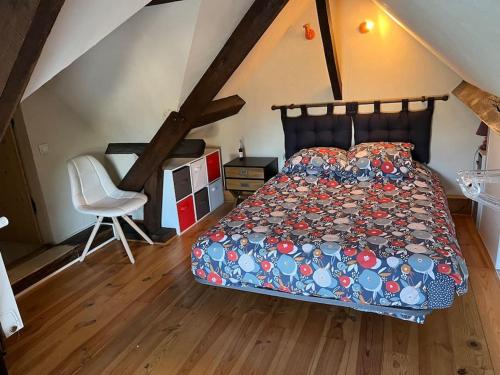 une chambre avec un lit et une chaise dans un grenier dans l'établissement Belle maison proche de chambord, à Huisseau-sur-Cosson