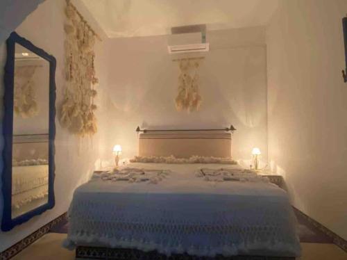 1 dormitorio con 1 cama con 2 lámparas y espejo en Dar Sandra Bizerte, en Bizerte