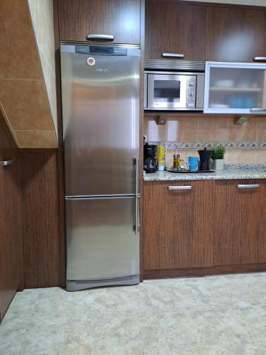 a stainless steel refrigerator in a kitchen with wooden cabinets at Casa Rural Torreblanca in Urroz