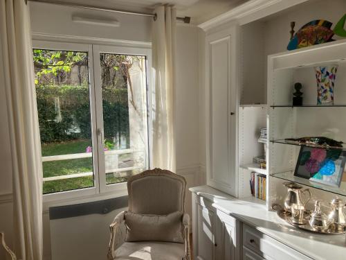 une chaise assise dans une pièce avec fenêtre dans l'établissement Elégant appartement sur jardin à Boulogne, à Boulogne-Billancourt