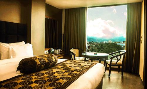 um quarto de hotel com uma cama, uma mesa e uma janela em HOTEL SHOOLIN GRAND em Guwahati