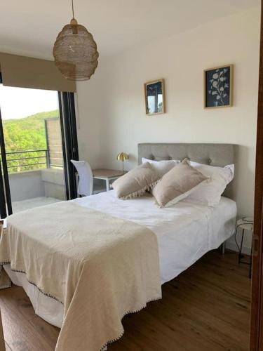 une chambre avec un lit avec des draps blancs et une fenêtre dans l'établissement Villa moderne - Favone, à Conca