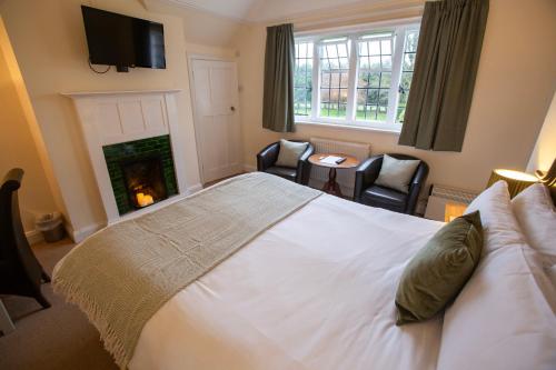 a bedroom with a large white bed and a fireplace at Little Court in Charminster