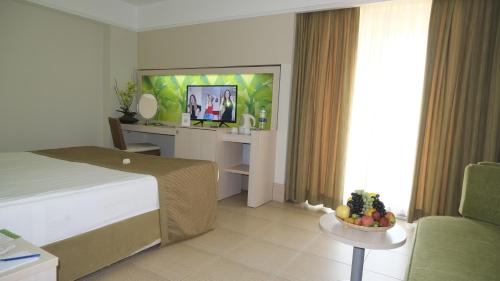 a hotel room with a bed and a table with a bowl of fruit at Ambassador Hotel & Spa- All Inclusive in Kemer