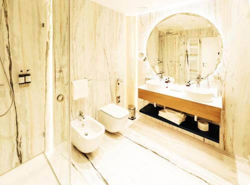 a bathroom with two sinks and a toilet and a mirror at Ana Hotels Europa Eforie Nord in Eforie Nord